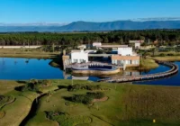 Vista aérea do condomínio com lago, clube e ponte de acesso — Condomínio Costa Serena
