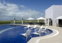 Piscina com espreguiçadeiras e área de lazer externa do condomínio — Condomínio Costa Serena