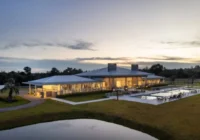 Clube social com piscina e lago ao entardecer — Estância dos Montes