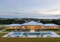 Clube social com piscinas e área de lazer ao entardecer — Estância dos Montes