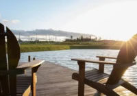 Cadeiras de madeira em deck sobre lago ao pôr do sol — Estância dos Montes