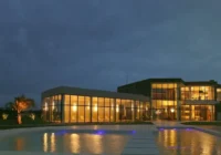 Fachada noturna do clube com piscina iluminada — Lagos de São Gonçalo