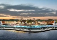 Área de lazer com piscina e bangalôs sobre o lago ao entardecer — Royal Lake